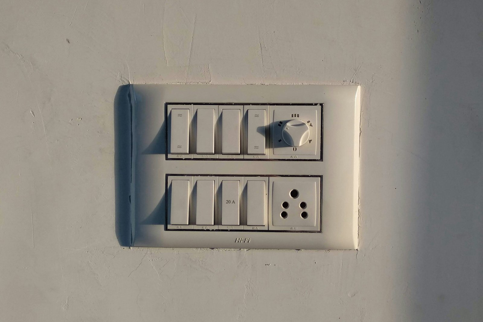 Hand stellt einen Lichtdimmer an der Wand ein
