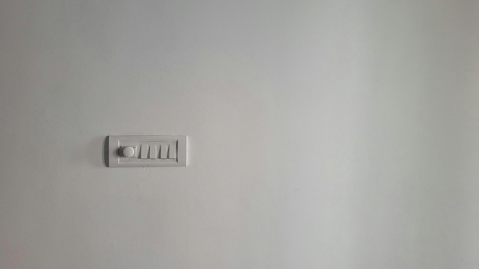 Ein runder Dimmerregler an einer weißen Wand