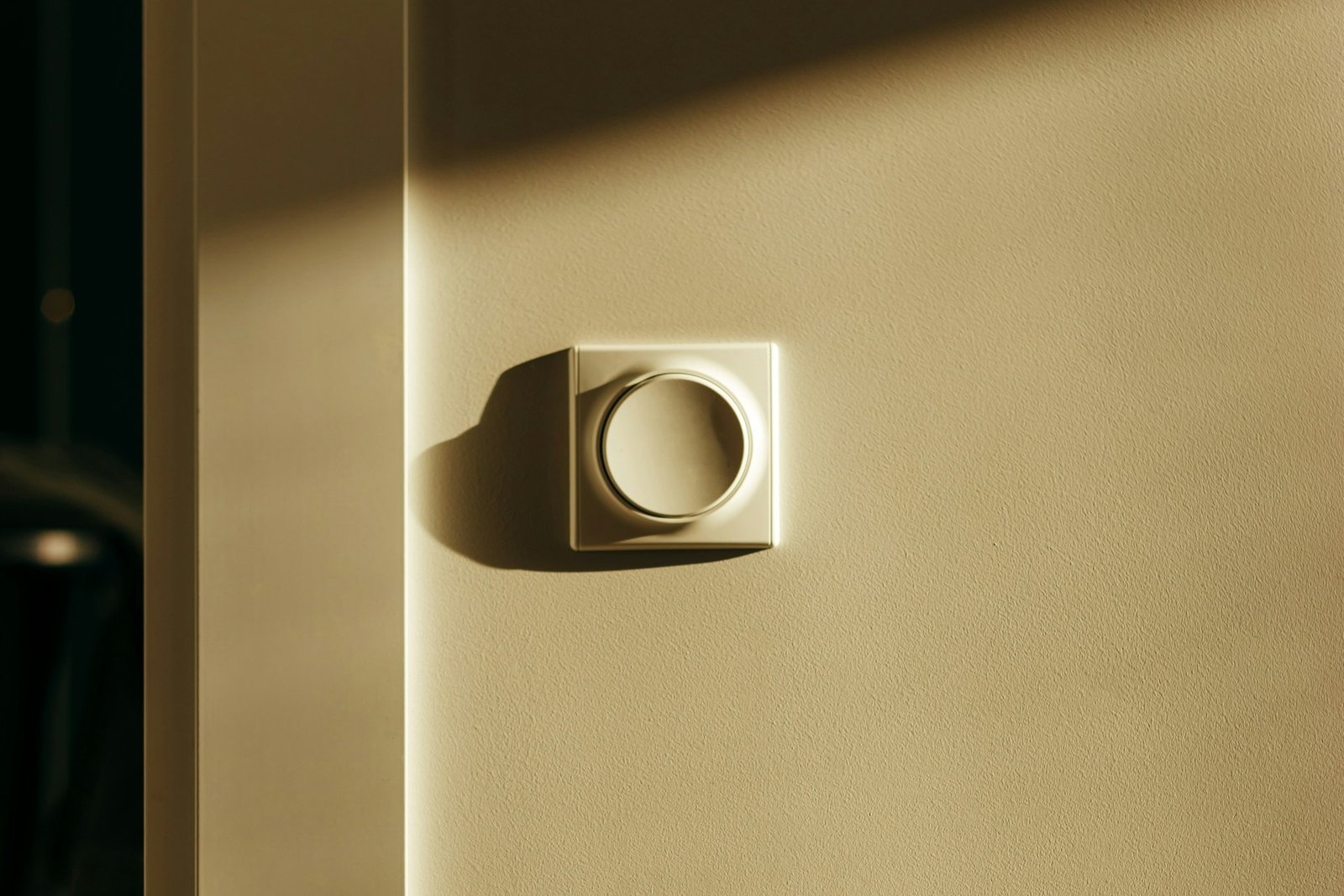 Hand dreht an einem Lichtdimmer an der Wand